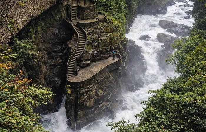 Wasserfall bei Baños mit Treppe entlang der Felswand in üppiger Natur