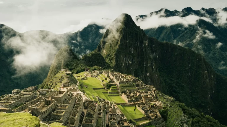Machu Picchu with terraced ruins set against steep Andean mountains in the mist
