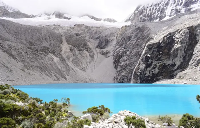 Turquoise blue Laguna 69 in the Cordillera Blanca with snow-capped mountains
